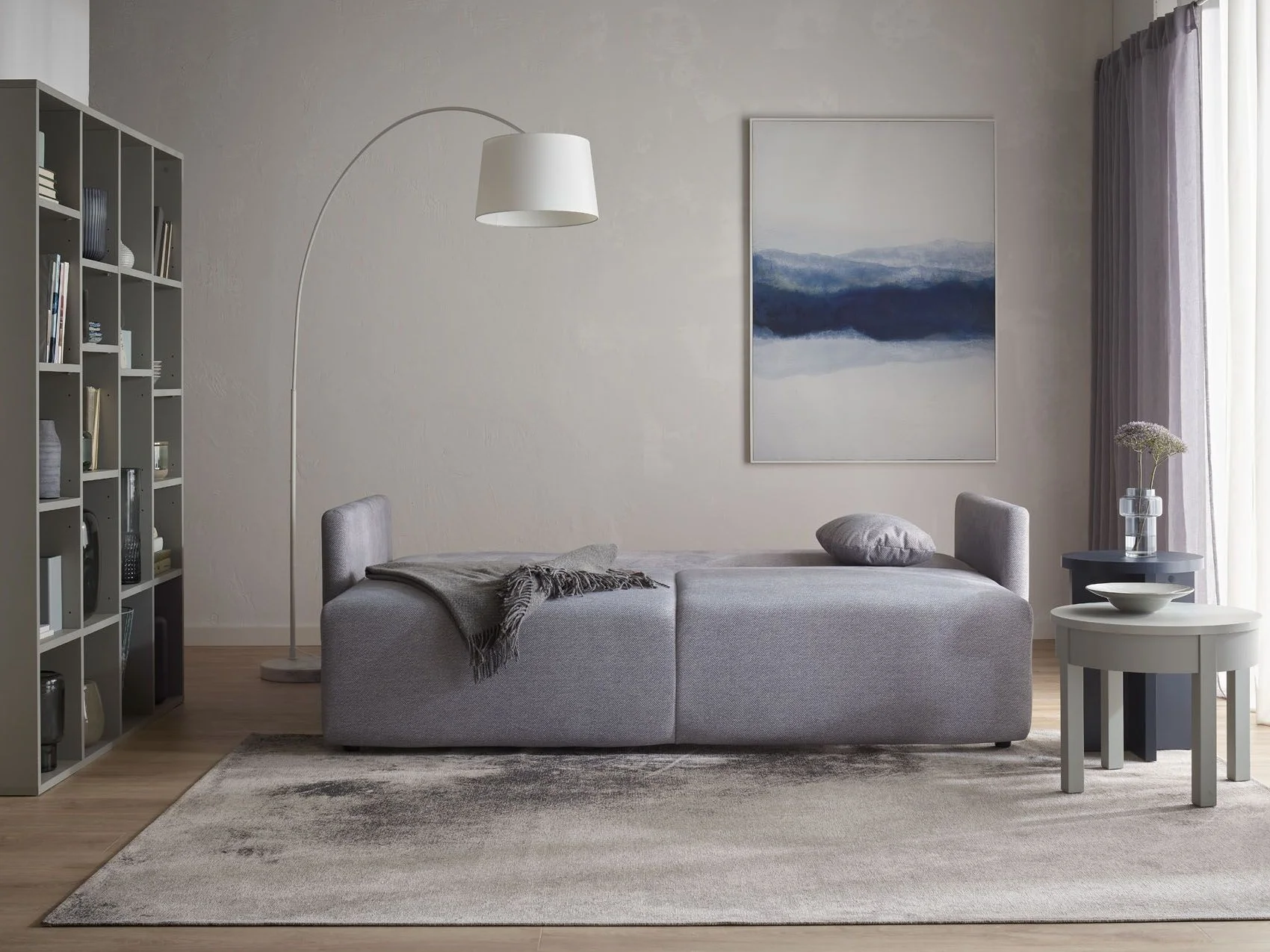 szara sofa na tle jasnej ściany
